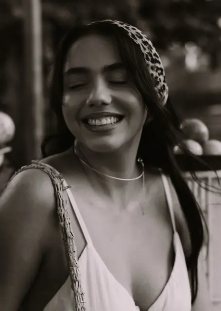 Retrato em preto e branco de mulher de lenço no cabelo, sorrindo de olhos fechados