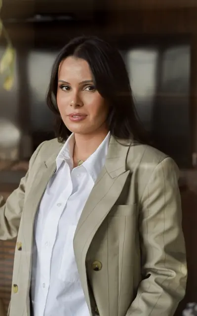 Mulher de blazer verde-claro e camisa branca, retrato de meio corpo em ambiente interno