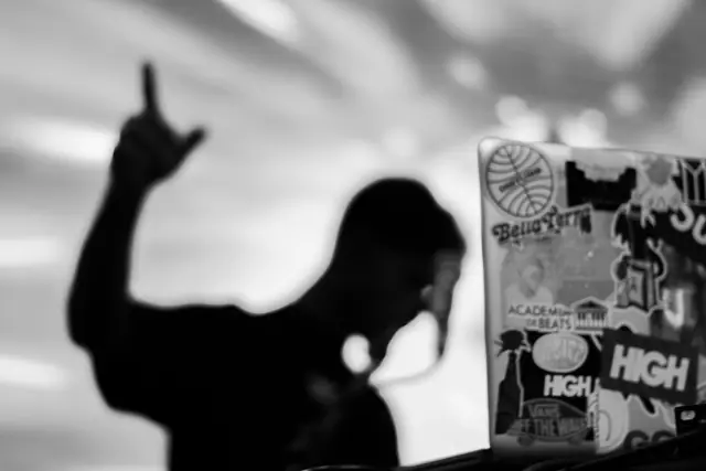 DJ de braço erguido em silhueta, preto e branco